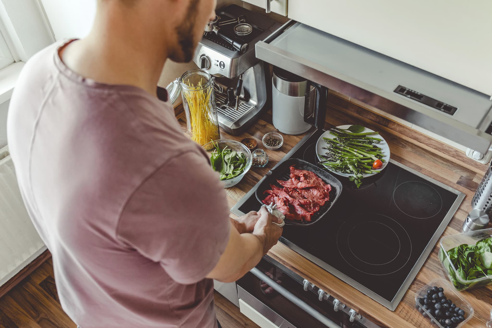 young-man-cooking-raw-meat-grill-pan.jpg